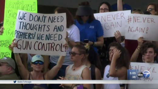 Protester holding sign saying 'We don't need thoughts and prayers - we need gun control'