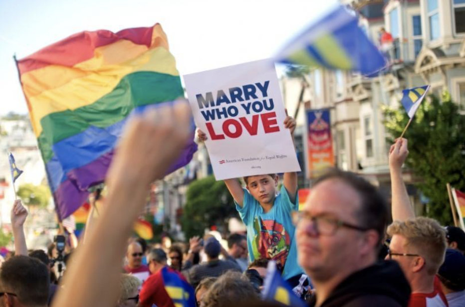 Group of campaigners holding a rainbow flag and a sign saying 'Marry who you love'