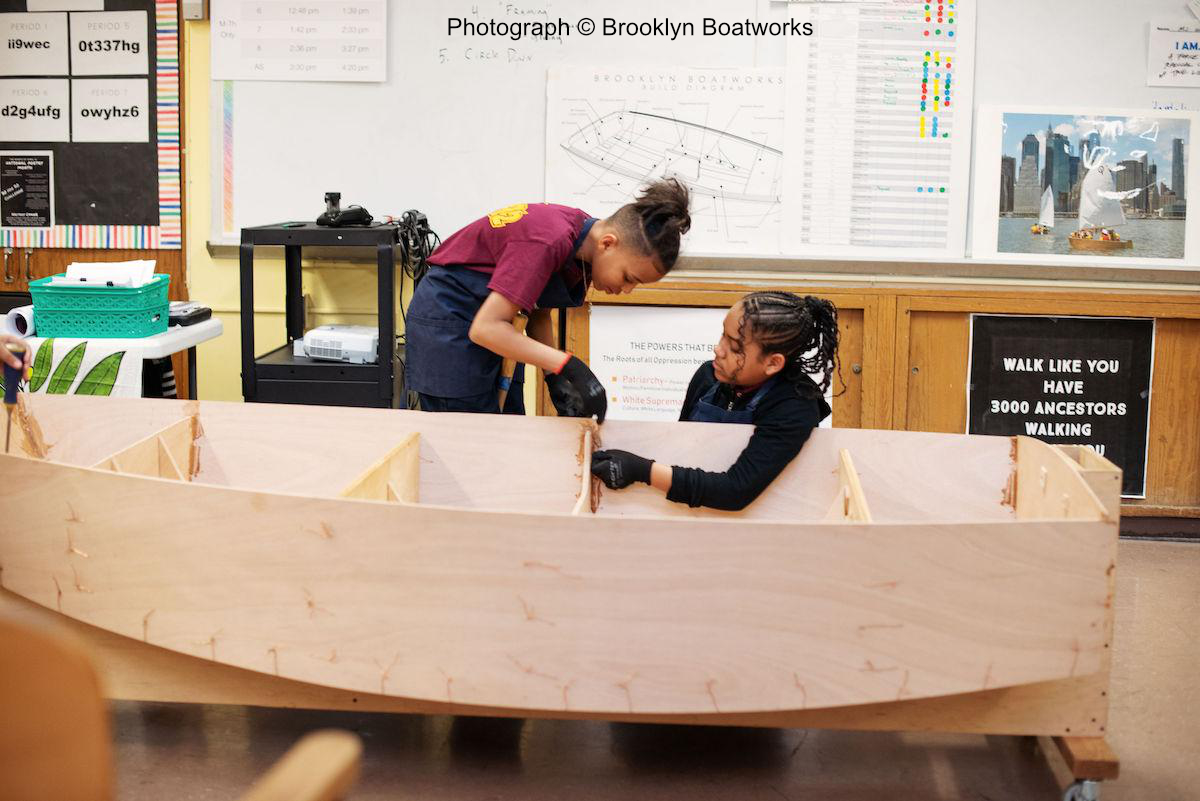 Photo of two young people building a small boat (Photo © Brooklyn Boatworks)